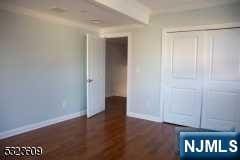 unfurnished bedroom featuring a closet and dark wood-type flooring