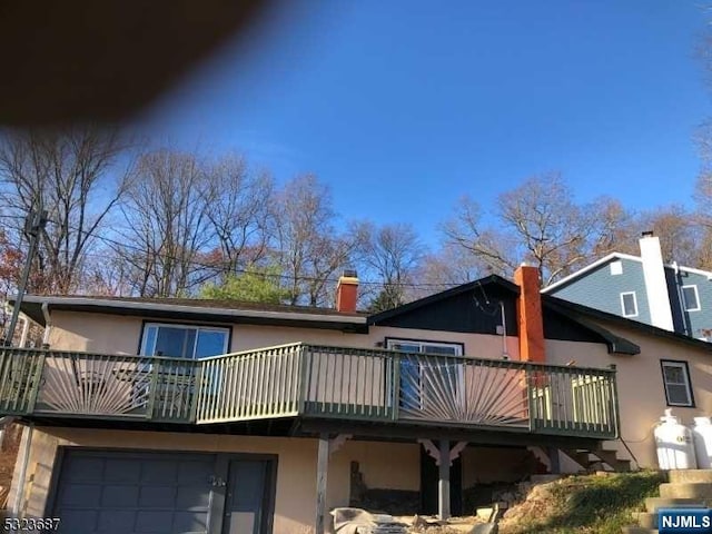 rear view of house with a garage and a deck