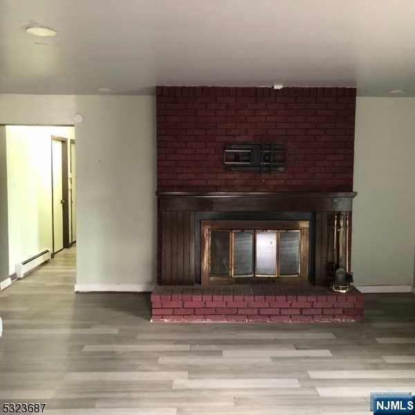 interior details featuring hardwood / wood-style floors, baseboard heating, and a brick fireplace