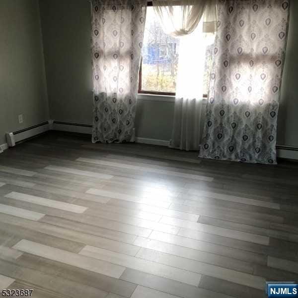 spare room featuring light wood-type flooring and baseboard heating