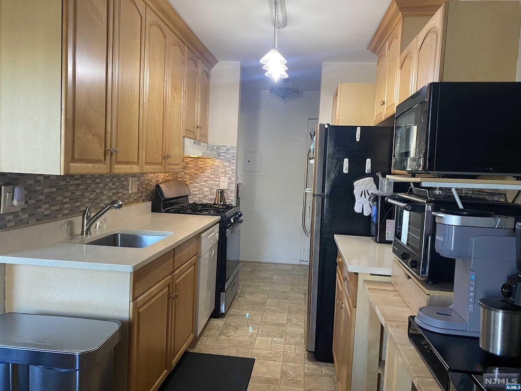 kitchen with pendant lighting, light brown cabinets, backsplash, black appliances, and sink