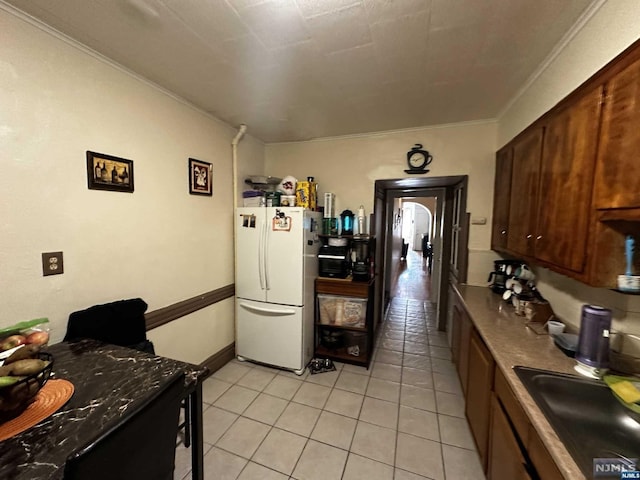 kitchen featuring crown molding, sink, light tile patterned floors, and white refrigerator