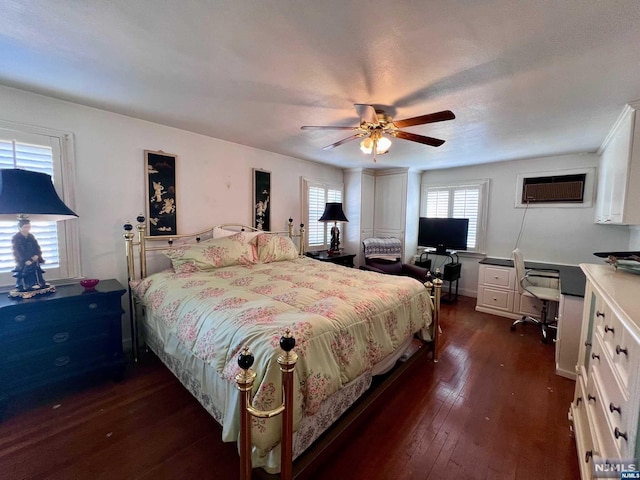 bedroom with dark hardwood / wood-style flooring, an AC wall unit, and ceiling fan