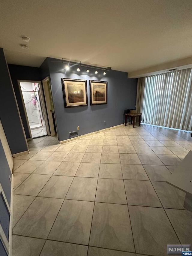 empty room with track lighting and light tile patterned flooring