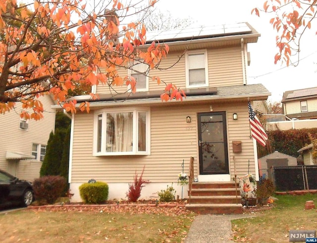 front facade featuring solar panels and a front lawn