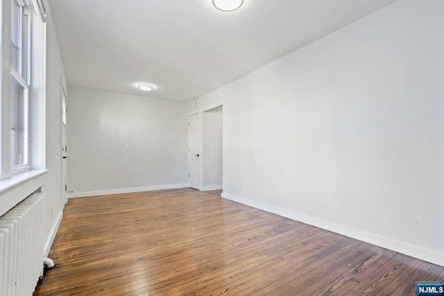 spare room with radiator heating unit and hardwood / wood-style floors