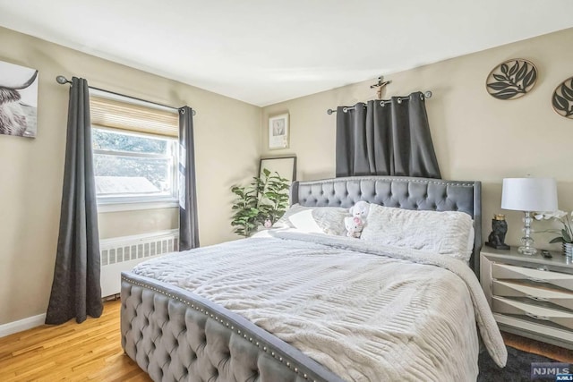 bedroom with light hardwood / wood-style floors and radiator heating unit