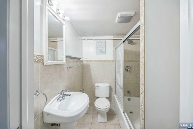 full bathroom with tile patterned floors, sink, toilet, enclosed tub / shower combo, and tile walls