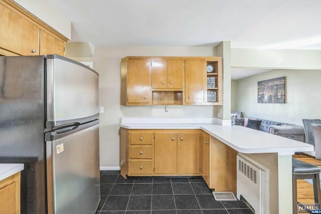 kitchen with kitchen peninsula, a kitchen breakfast bar, stainless steel refrigerator, and radiator