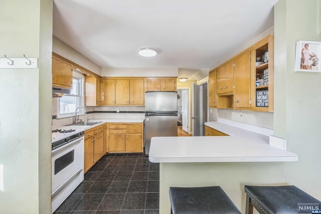 kitchen featuring kitchen peninsula, stainless steel fridge, white range, sink, and a breakfast bar area