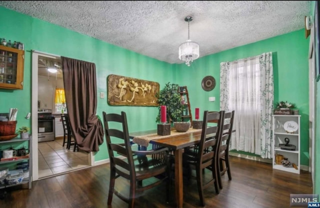 dining area with dark hardwood / wood-style flooring, a textured ceiling, and an inviting chandelier