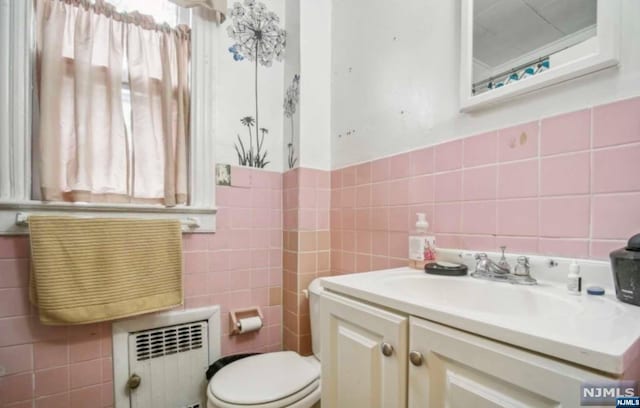 bathroom featuring radiator heating unit, vanity, tile walls, and toilet