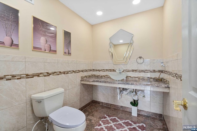 bathroom featuring toilet and tile walls