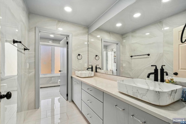 bathroom featuring tile patterned floors, vanity, baseboard heating, tile walls, and toilet