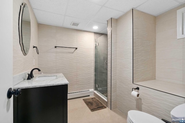 bathroom with vanity, toilet, tile walls, and a baseboard heating unit