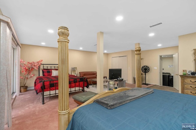 bedroom featuring baseboard heating, washing machine and dryer, light carpet, and decorative columns