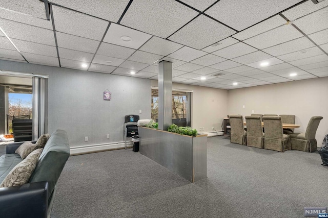 interior space featuring baseboard heating, a wealth of natural light, a drop ceiling, and carpet