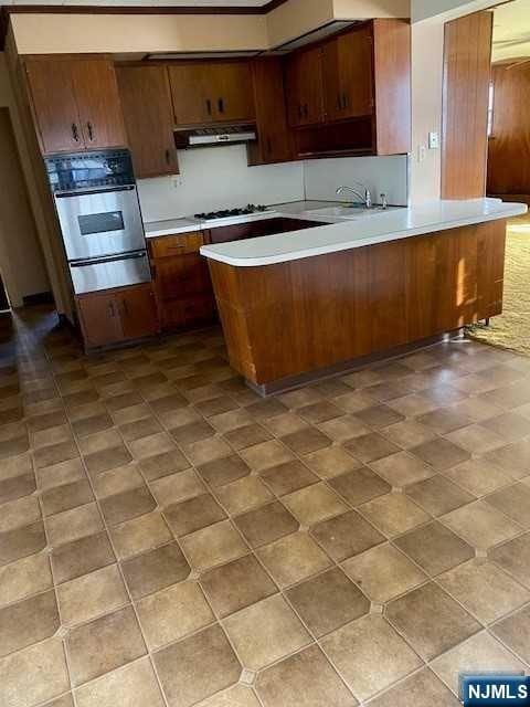 kitchen with sink, gas stovetop, kitchen peninsula, oven, and extractor fan