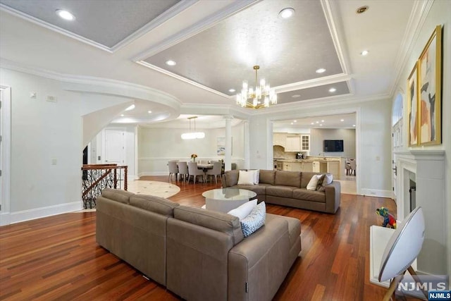 living room with dark hardwood / wood-style floors, crown molding, and a notable chandelier