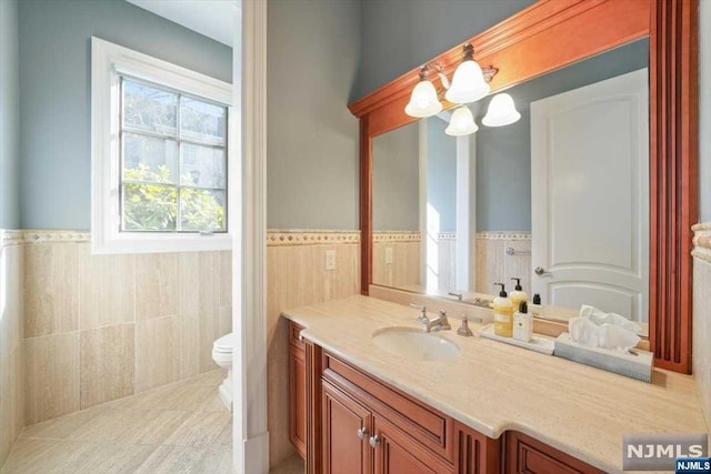 bathroom with vanity, toilet, and tile walls