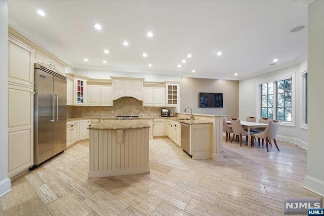 kitchen with kitchen peninsula, a center island, stainless steel appliances, and light stone countertops