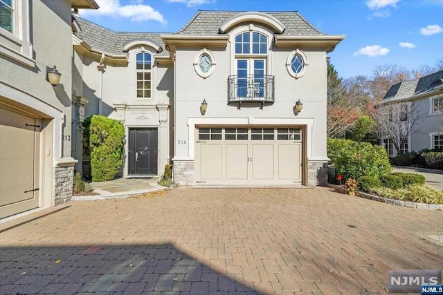 french provincial home with a balcony and a garage