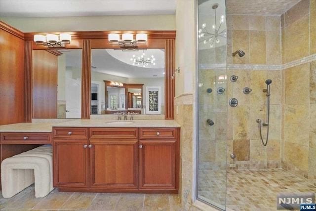 bathroom featuring vanity, an inviting chandelier, and a shower with door