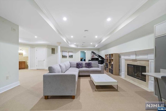 carpeted living room featuring a tray ceiling, a fireplace, and ornamental molding