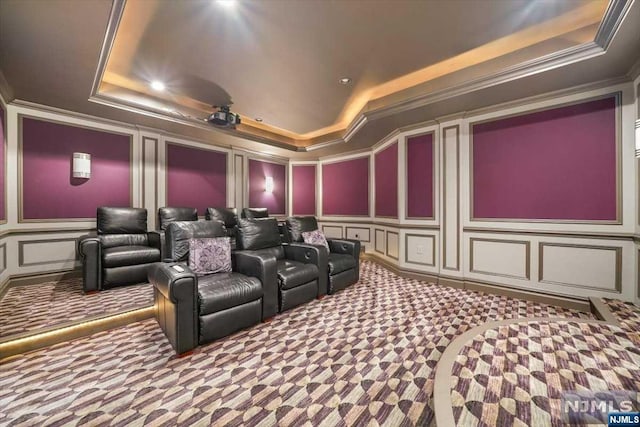 home theater room with carpet floors, crown molding, and a tray ceiling