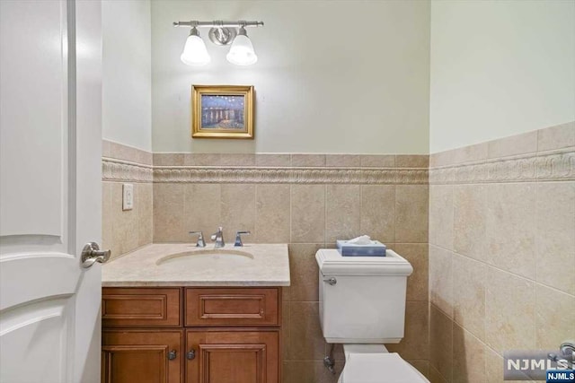 bathroom featuring vanity, toilet, and tile walls