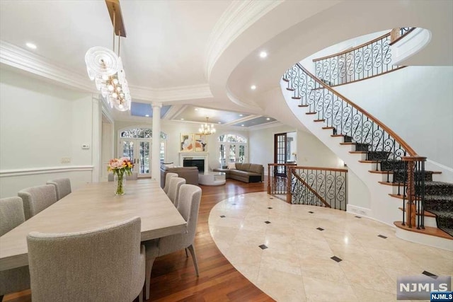 dining area featuring wood-type flooring, crown molding, and a notable chandelier