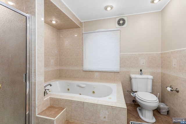 bathroom with tile patterned floors, separate shower and tub, toilet, and tile walls