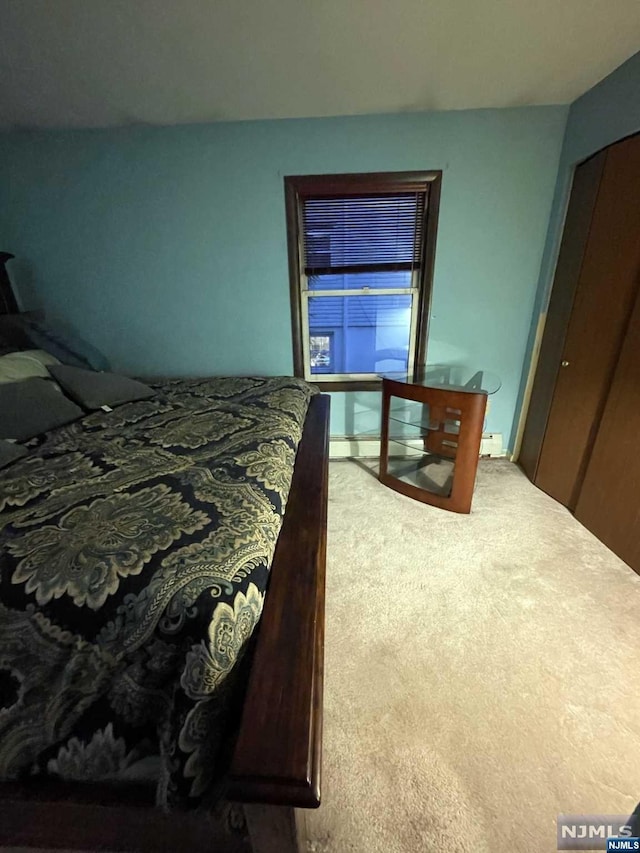 carpeted bedroom featuring a baseboard heating unit and a closet