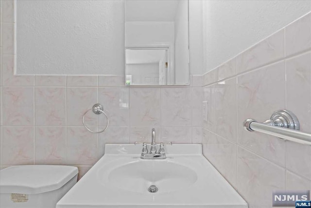 bathroom with vanity, tile walls, and toilet