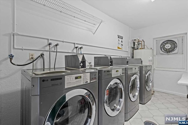 washroom with washer and dryer, light tile patterned flooring, and water heater