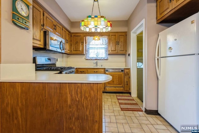 kitchen featuring sink, kitchen peninsula, stainless steel appliances, and hanging light fixtures