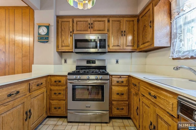 kitchen with kitchen peninsula, sink, light tile patterned flooring, and appliances with stainless steel finishes