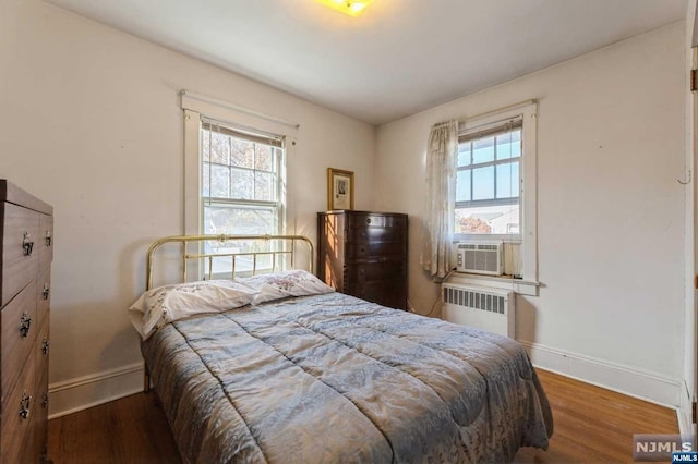 bedroom with radiator heating unit, cooling unit, and hardwood / wood-style floors