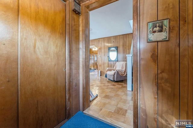 corridor with light parquet floors and wood walls