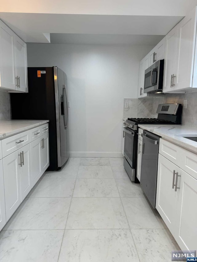 kitchen featuring light stone counters, white cabinetry, appliances with stainless steel finishes, and tasteful backsplash