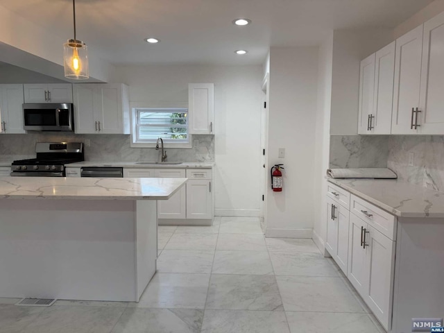 kitchen featuring sink, white cabinets, hanging light fixtures, and appliances with stainless steel finishes