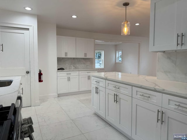 kitchen featuring decorative backsplash, light stone countertops, white cabinets, and pendant lighting