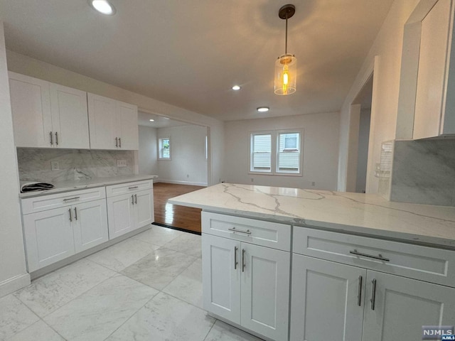 kitchen with backsplash, light stone countertops, white cabinets, and decorative light fixtures