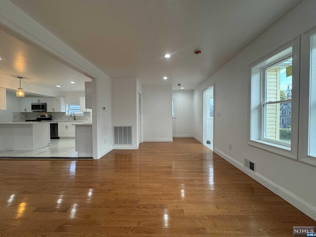 unfurnished living room with sink and light hardwood / wood-style floors