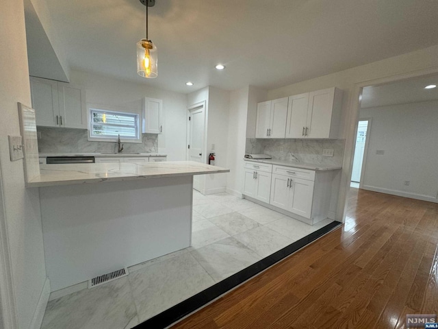 kitchen with sink, tasteful backsplash, light hardwood / wood-style flooring, pendant lighting, and white cabinets