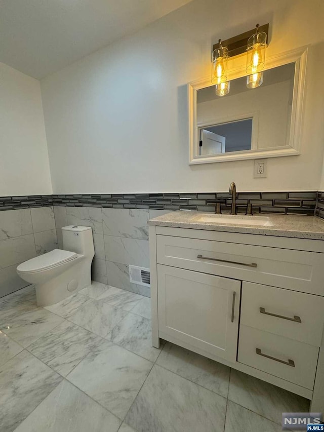 bathroom with vanity, tile walls, and toilet