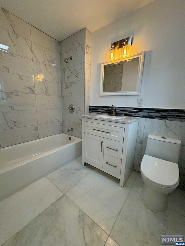 full bathroom featuring vanity, toilet, tile walls, and tiled shower / bath