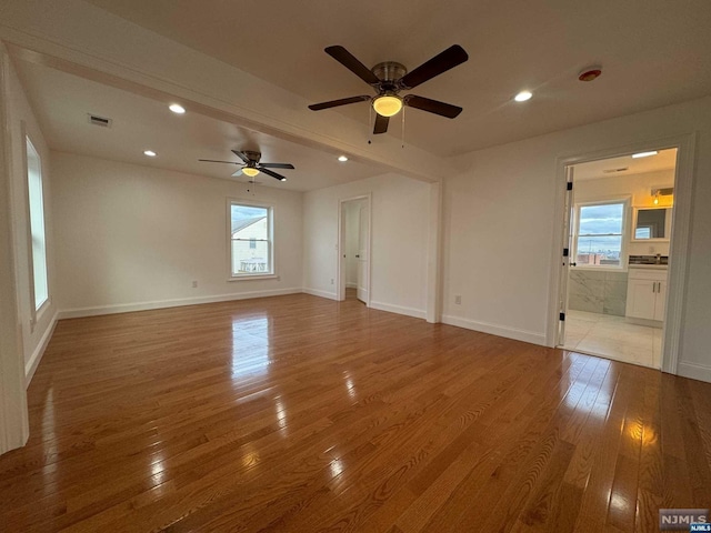 empty room with light hardwood / wood-style flooring, plenty of natural light, and ceiling fan