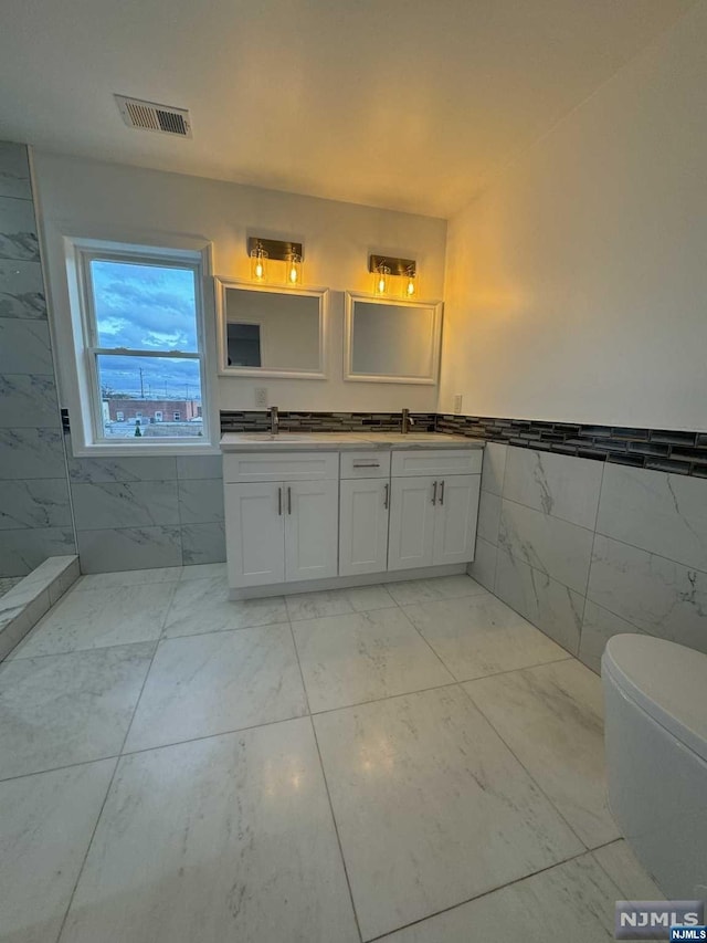 bathroom featuring vanity, toilet, and tile walls