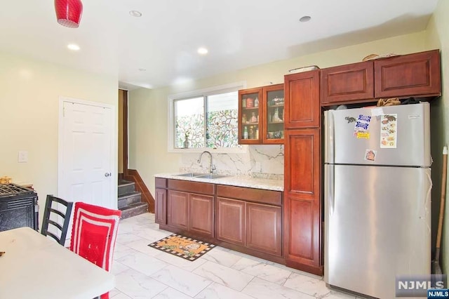 kitchen with decorative backsplash, sink, and stainless steel refrigerator